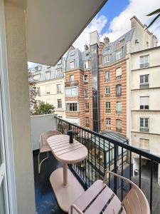 een balkon met een tafel en stoelen en een gebouw bij design apartment in Parijs