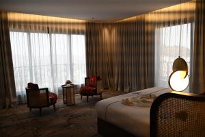 アブハにあるGolden Balcon Hotelのベッド、椅子、窓が備わるホテルルームです。