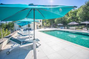 a pool with two chairs and a blue umbrella at Charmante villa avec grande piscine au calme in Callian