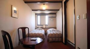 a small room with a table and a bed and a table and a table sidx at HotelNewYama in Yamanouchi