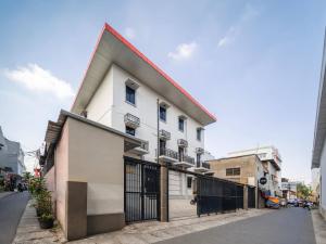 a white building with a red roof on a street at Cove Oekude Residence in Jakarta