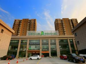 a large building with cars parked in a parking lot at Jinjiang Inn Style Tianjin Wuqing Traditional Chinese Medical Hospital in Tianjin