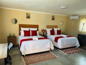a bedroom with two beds with red and white sheets at Hope Villa Luxury Accomodation in Odendaalsrus +43 photos