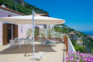 une terrasse avec un parasol, une table et des chaises dans l'établissement Le Anfore 2 - Amalfi Coast, à Conca dei Marini