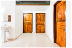 deux portes en bois dans une pièce blanche avec un lavabo dans l'établissement Hotel Shree Laxmi Resorts - Patia Railway Station- Fully Air Conditioning Hotel - Luxury & Spacious Room -A Premium Hotel, à Cuttack