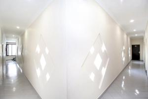 a hallway with white walls and white tile floors at Hotel O Basera Boutique in Amritsar
