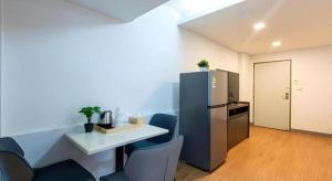 a kitchen with a table and a refrigerator and chairs at Hotel Holm Bangkok in Bangkok