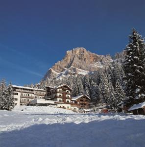 un edificio nella neve con una montagna sullo sfondo di Hotel San Martino a San Martino di Castrozza