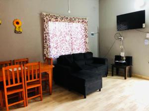 ein Wohnzimmer mit schwarzem Sofa und einem Tisch in der Unterkunft Dúplex Birnbaum Ruiz Diaz in Roque González de Santa Cruz