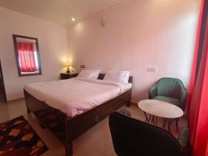 a bedroom with a bed and a table and a chair at King's Paradise Resort by RIHS in Kanatal