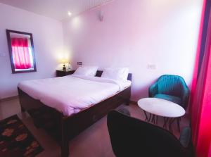 a bedroom with a bed and a table and two chairs at King's Paradise Resort by RIHS in Kanatal