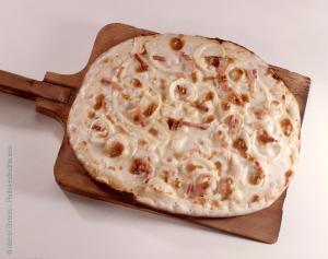 a pizza sitting on a wooden cutting board at Chambre d hote in Sarralbe