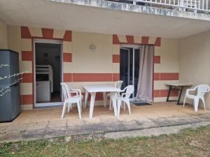einen Tisch und Stühle auf der Terrasse eines Hauses in der Unterkunft Appartement pour 4 à 6 personnes avec piscine in Le Verdon-sur-Mer