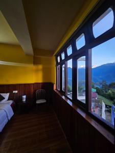 a bedroom with a bed and a large window at Sikkimese Inn Pelling in Pelling