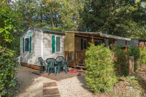 ein winziges Haus mit einem Tisch und Stühlen im Hof in der Unterkunft Mobil-home in La Roque-dʼAnthéron