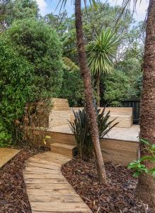 a wooden path in a garden with trees and bushes at The Peacock House in Wellington