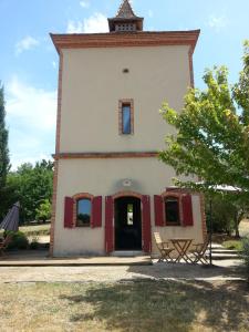an old building with red shutters and a tower at Le Pigeonnier de Roudet in Larrazet +14 photos