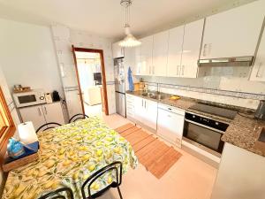 a kitchen with white cabinets and a table in it at Sa Calma Marina A Tranquil Mediterranean Retreat in Sa Ràpita +13 photos