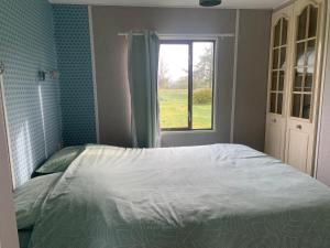 une chambre avec un lit et une fenêtre dans l'établissement Mobil Home Vintage à la Ferme des buttons, à Rosnay
