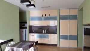 a kitchen with white cabinets and a table and a dining room at Amber apartment in Palanga