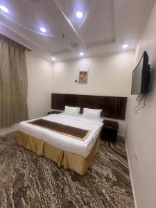 Un dormitorio con una cama grande y un televisor de pantalla plana. en فندق اوتاد المتحدة عبالله الخياط, en La Meca 36 fotos más