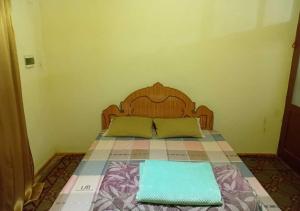 a bed with a wooden headboard and two green pillows at Vila 1926 Entrepreneur in Polisi i Vogël