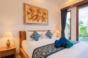 a bedroom with a bed and a painting on the wall at Pondok Sura in Ubud +30 photos