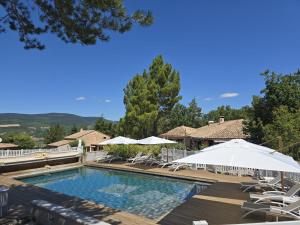 a swimming pool with white umbrellas and chairs at Domaine du Val de Sault in Sault-de-Vaucluse