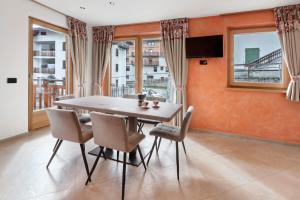 a dining room with a table and chairs and windows at Bait Dal Pa Livigno in Livigno