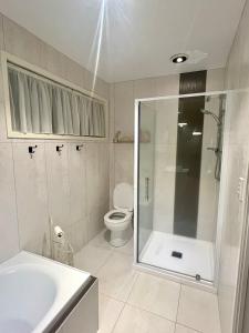 a bathroom with a shower and a toilet and a sink at Sunny Matua, Private Suite, Quiet Stay, 5star Bed in Tauranga