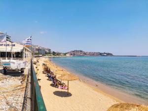 a beach with umbrellas and people sitting on the beach at Sea Whisper Luxury Apartments Kavala in Kavala