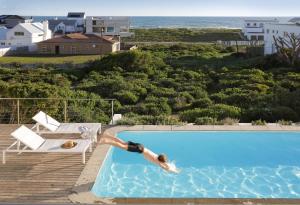 a man diving into a swimming pool next to the ocean at Blanc de Blanc in Yzerfontein +19 photos