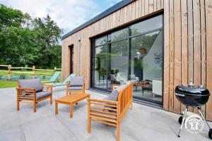 a wooden house with a grill and chairs on a patio at Les asphodeles in Muzillac