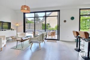 a living room with white furniture and a large window at Les asphodeles in Muzillac