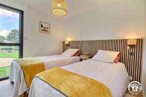 two beds in a room with a window at Les asphodeles in Muzillac