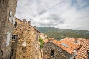 a group of stone buildings with mountains in the background at La maison de Mina in Olmeto