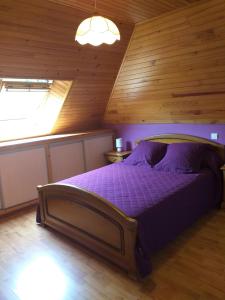 ein Schlafzimmer mit einem lila Bett in einer Holzdecke in der Unterkunft Chez Maurice et Sylvie in Laveissière