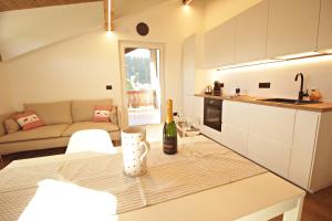 a kitchen and living room with a table with a bottle of wine at Guest House Dezulian in Castello di Fiemme +1 photo