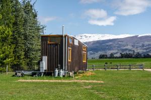 une petite maison dans un champ avec des montagnes en arrière-plan dans l'établissement Tarras Tiny Haven - Wake up to Breathtaking Mountains, à Tarras