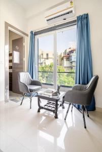 a living room with two chairs and a table and a large window at The Royal Harmony in Greater Noida