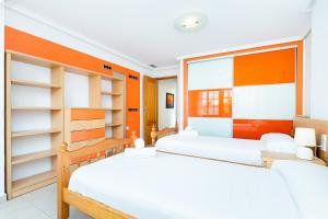 Un dormitorio con dos camas y una pared naranja. en Maravillas, en La Mata