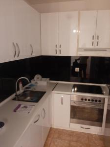 ロズニツァにあるApartman Loznica Centarのキッチン(白いキャビネット、シンク、コンロ付)
