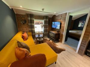 a living room with a yellow couch and a tv at Charming apartment with lodgefeeling in Hemsedal