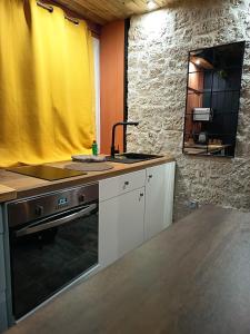 una cucina con un lavandino e una stufa e una tenda gialla di La Cachette des Tisserands, Hammam, Balneo a Pontivy