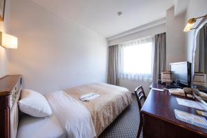 a hotel room with a bed and a desk with a computer at Kamaishi Bay City Hotel in Kamaishi +44 photos