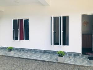 three windows on a white building with potted plants at Shaan guest house in Pelwadiya