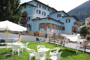 a group of white chairs and tables in front of a building at Hotel Ancora in Moena