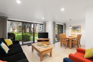 a living room with a couch and a table at Paradise at The Bay in Nelson Bay