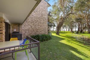 a patio with a table and chairs and a yard at Paradise at The Bay in Nelson Bay