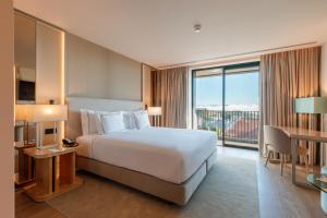 a hotel room with a bed and a large window at Meliá São João da Madeira in São João da Madeira